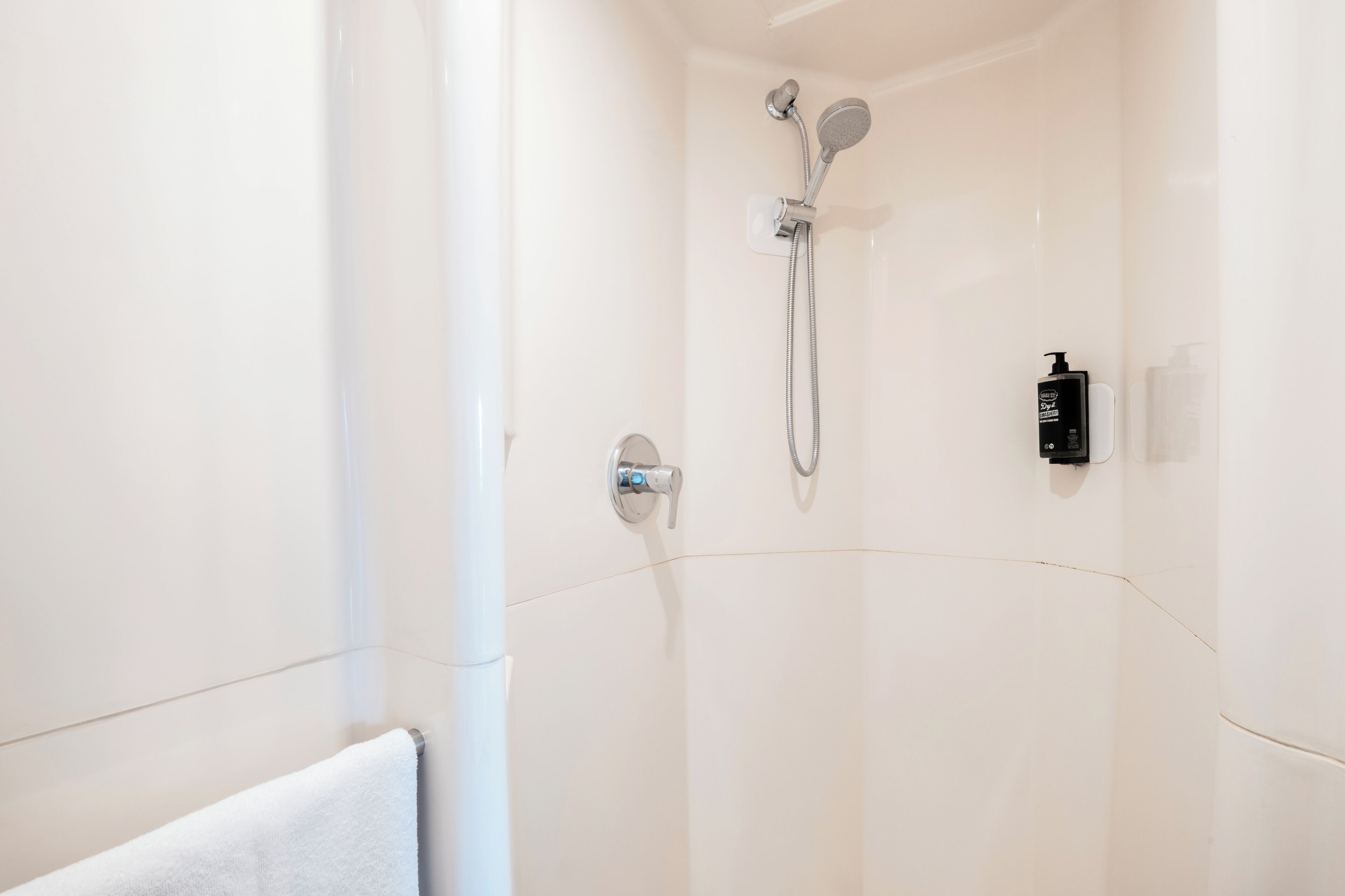 A modern shower with a handheld showerhead and a wall-mounted faucet.