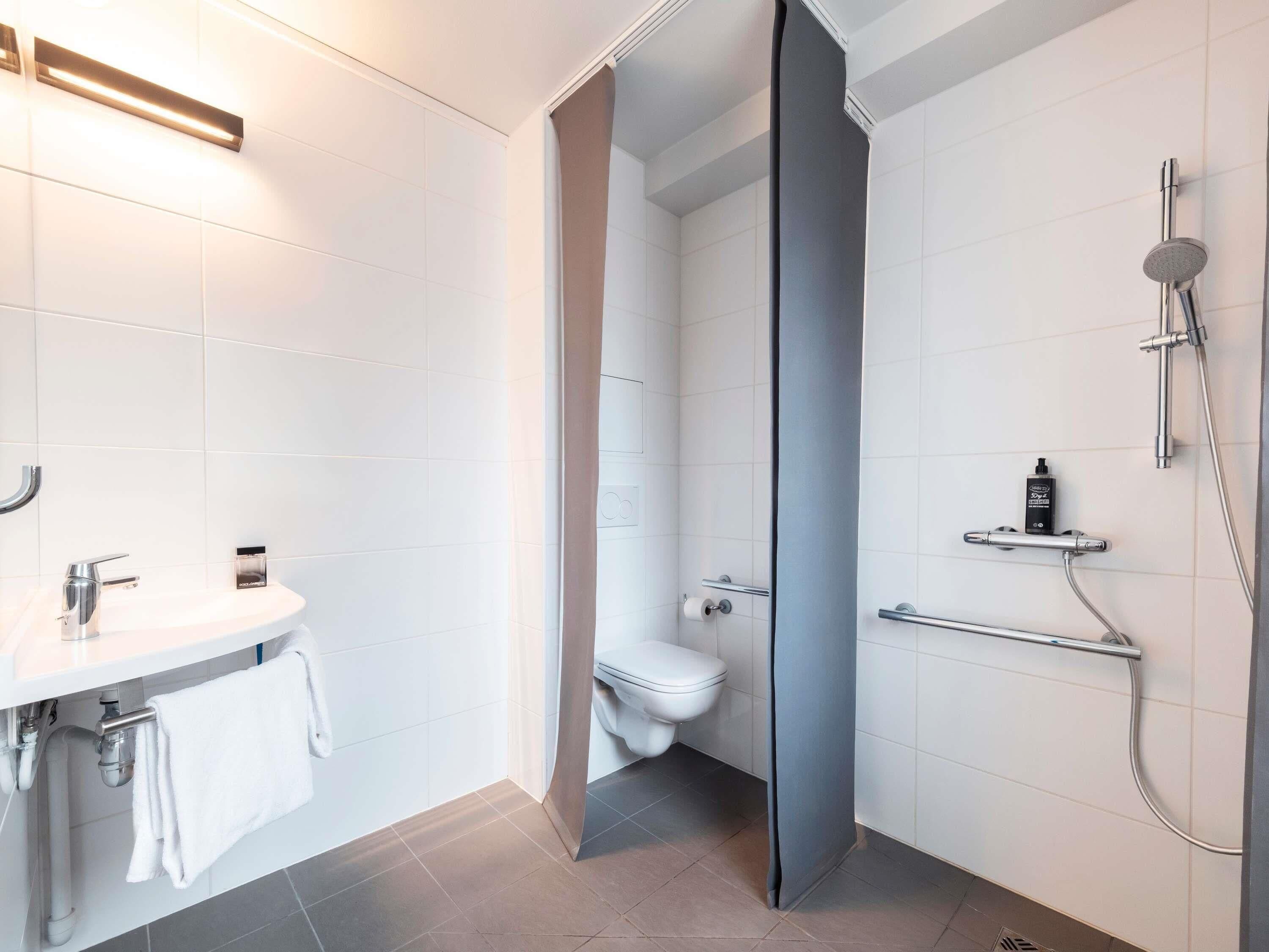 A modern bathroom with a white sink, toilet, and shower area.