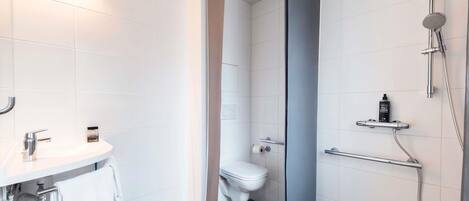 A modern bathroom with a white sink, toilet, and shower area.