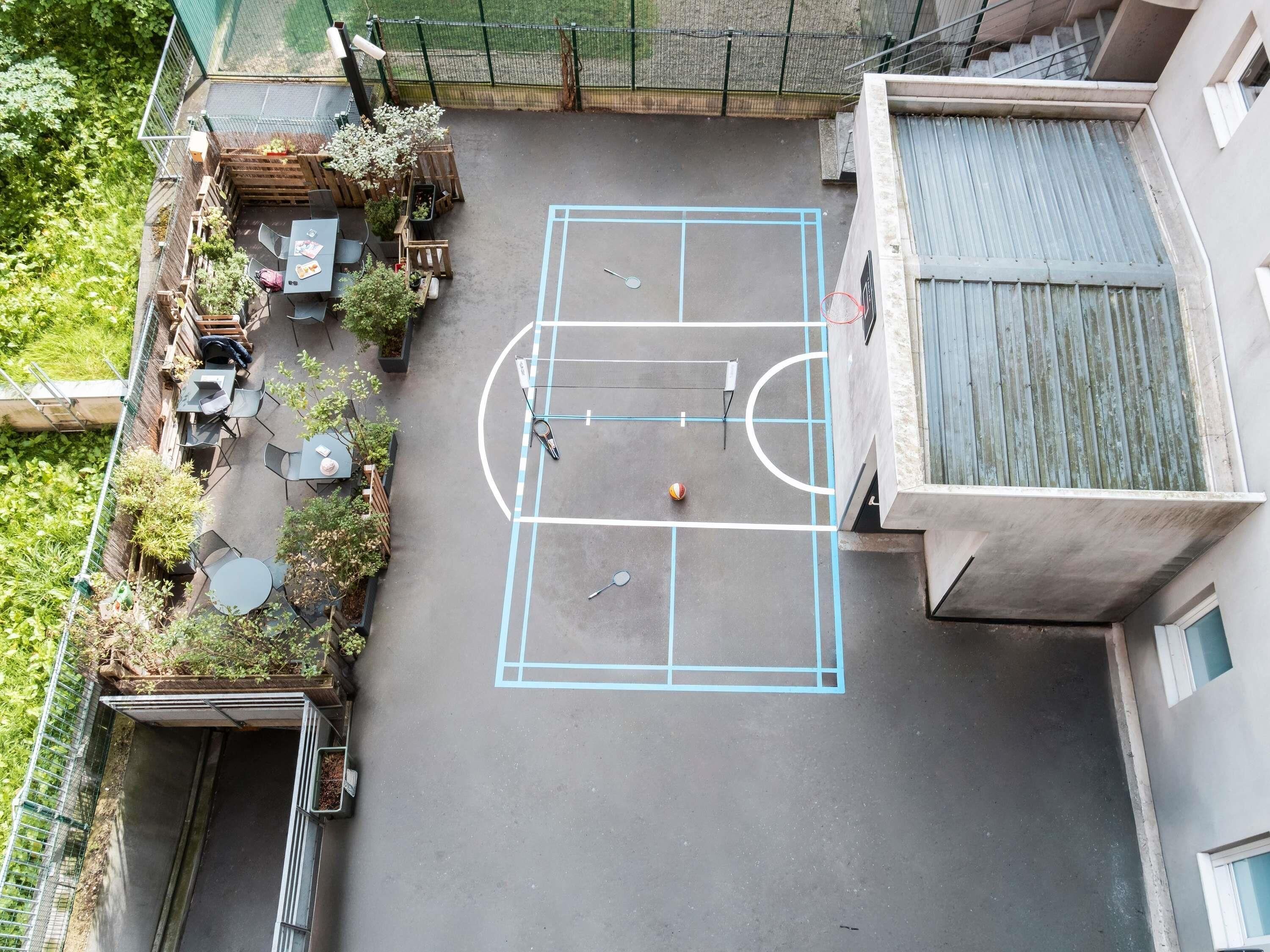 An outdoor basketball court with seating and a net.