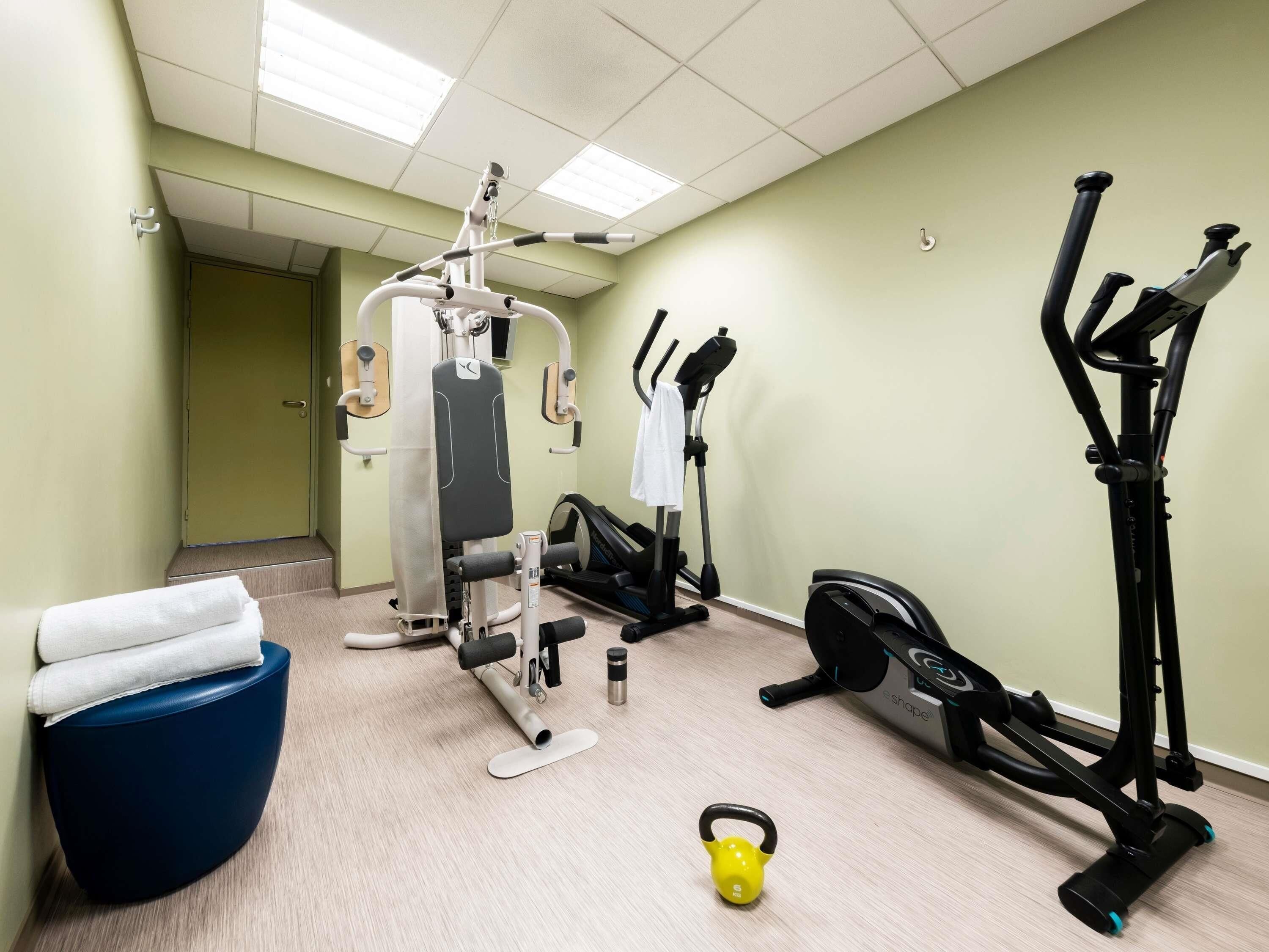 A fitness room with exercise equipment, a blue chair, and a kettlebell.
