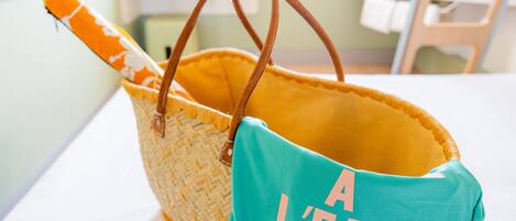 A wicker basket with brown handles and a teal bag with "A L'EAU" text.