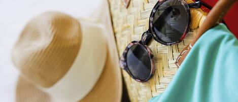 A straw hat, sunglasses, and a woven bag on a surface.