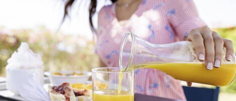 Una persona sirviendo jugo de naranja en un vaso.