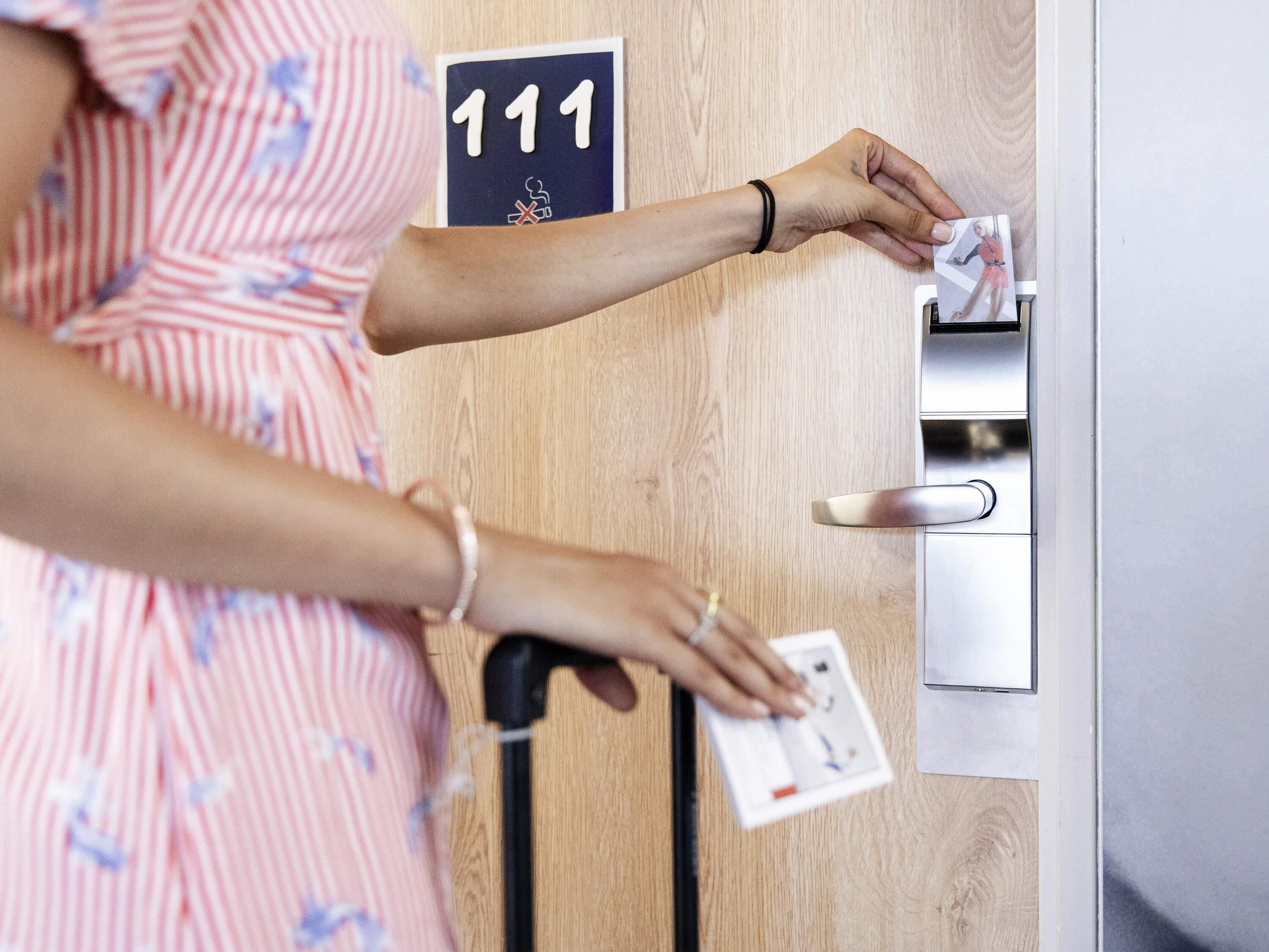 Une personne utilise un lecteur de carte pour accéder à une pièce dont la porte est munie d’une plaque indiquant le numéro 111.
