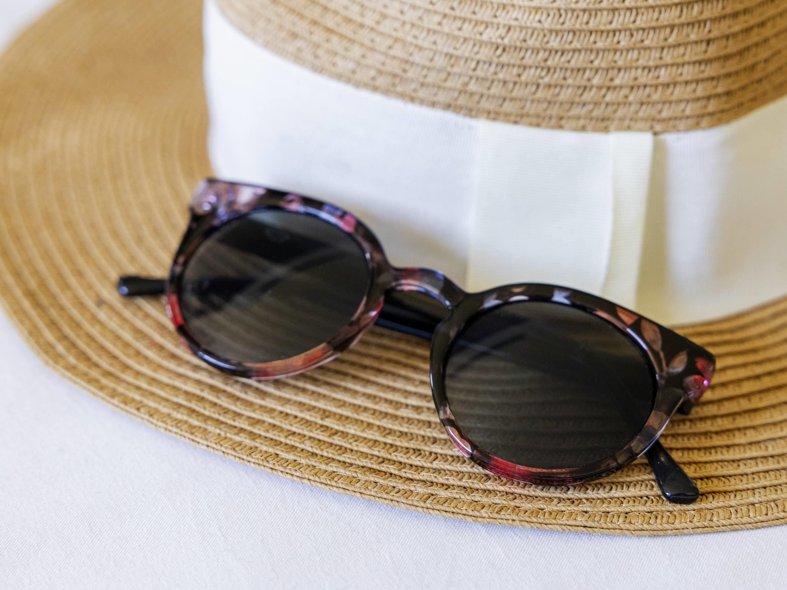 A straw hat and a pair of sunglasses with a reflective surface.