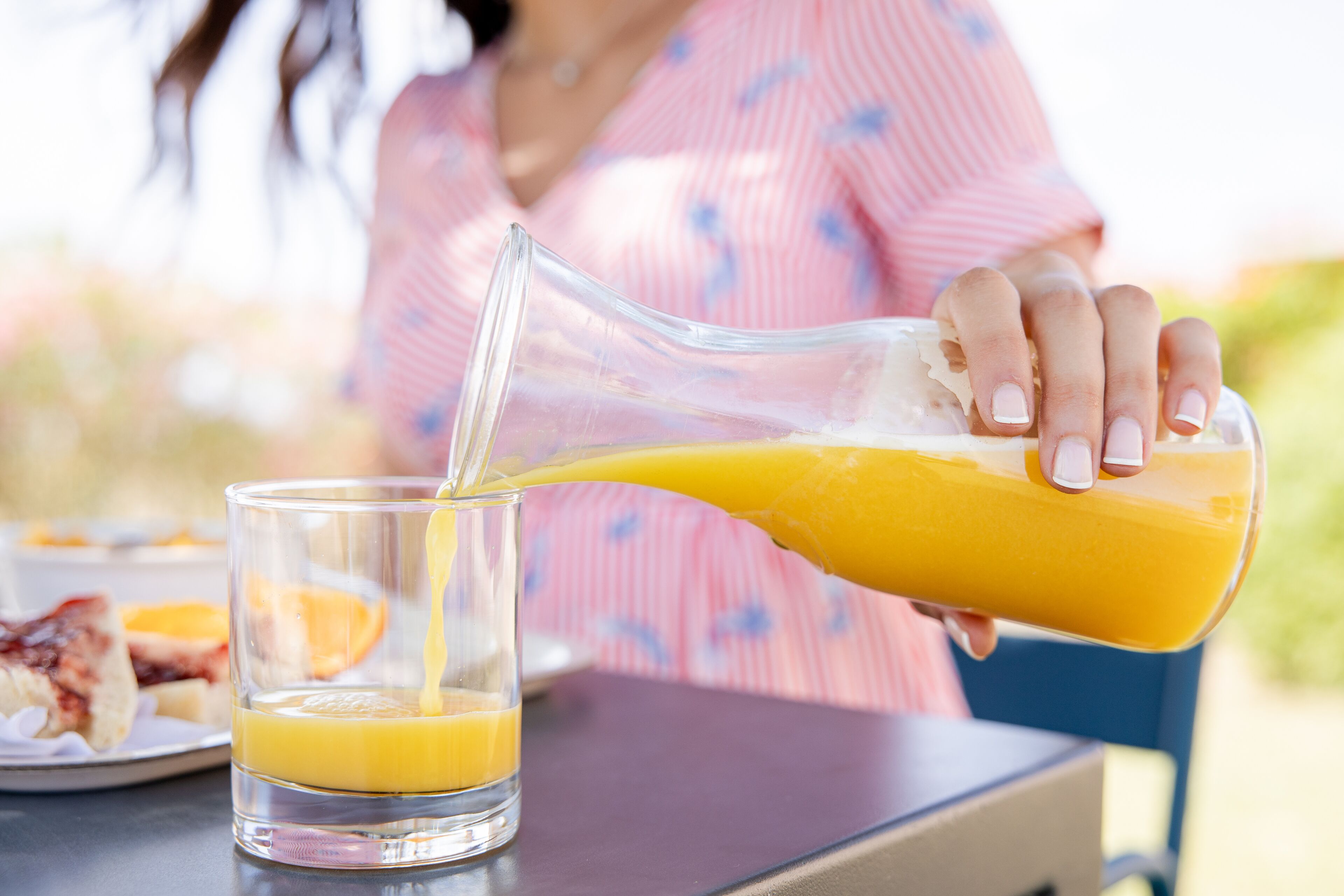 Iemand giet sinaasappelsap in een glas.