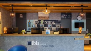 Een modern ontworpen receptiebalie met het logo en de naam van de accommodatie, "ibis budget Paris la Villette".