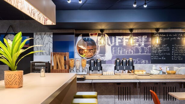 Een modern café interieur met een bar, zitplaatsen en een krijtbordmenu.