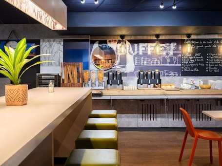 A modern café interior with a bar area, seating, and a chalkboard menu.. ibis budget Paris La Villette 19eme