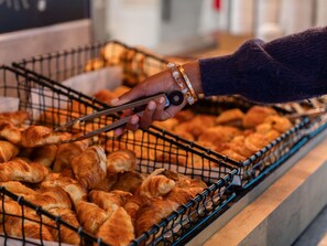 A hand selecting pastries from a wire basket.