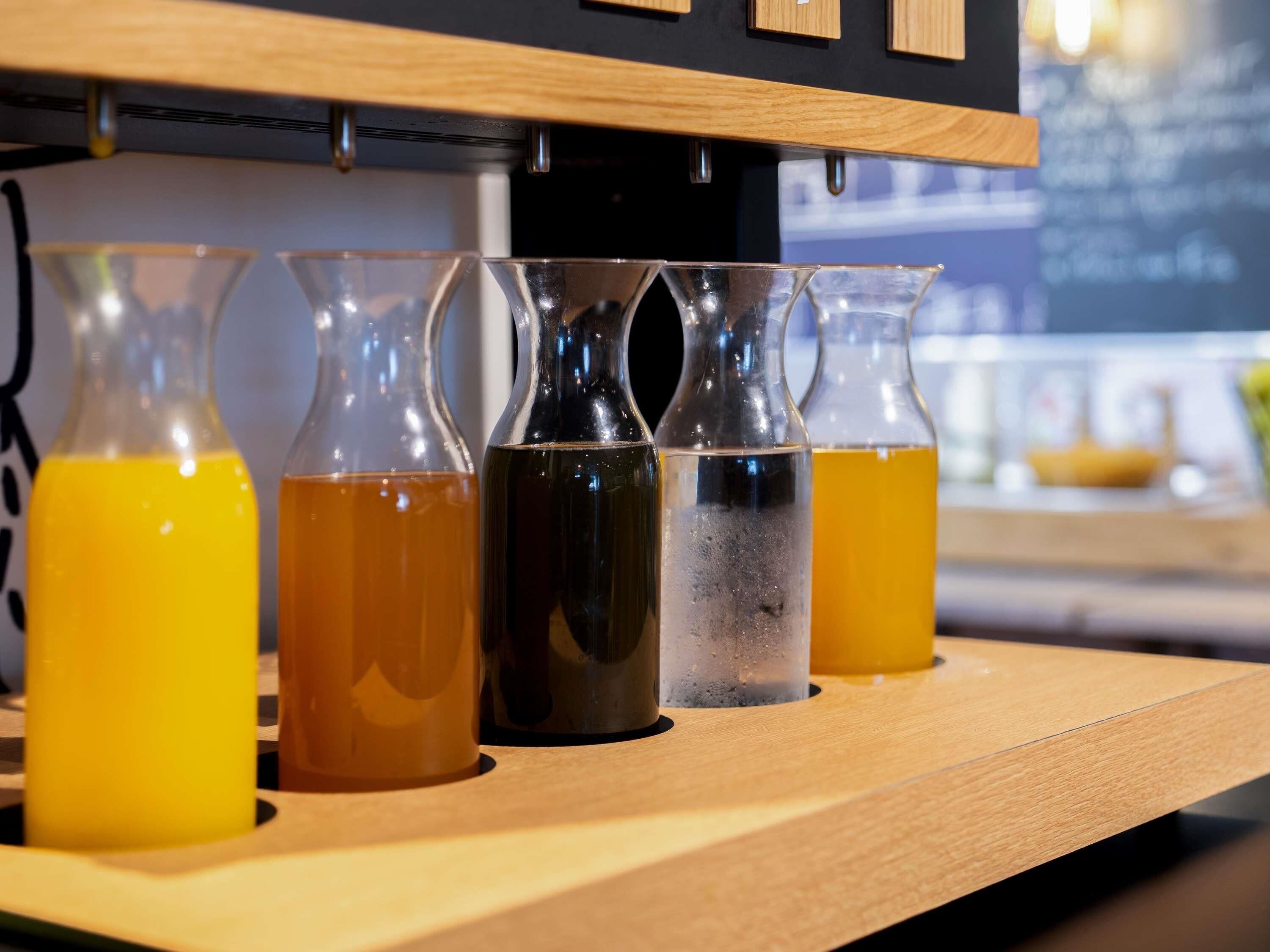 A wooden bar counter with four glass bottles containing different colored liquids.