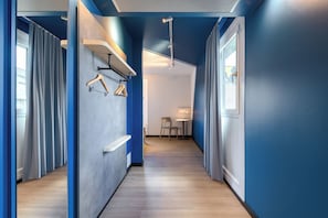 Un pasillo con paredes azules, suelo de madera y una zona de estar con una mesa y sillas.