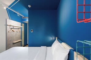 A modern bedroom with a large bed, a wardrobe, and a wall-mounted heater.