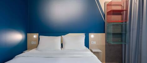 A modern hotel room with a large bed, two bedside tables, and a built-in wardrobe with a red and green color scheme.