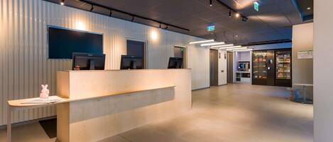 A reception area with a counter, two monitors, and a vending machine.