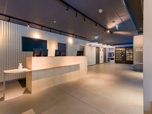 A reception area with a counter, two monitors, and a vending machine. - ibis budget Leipzig City (Leipzig)