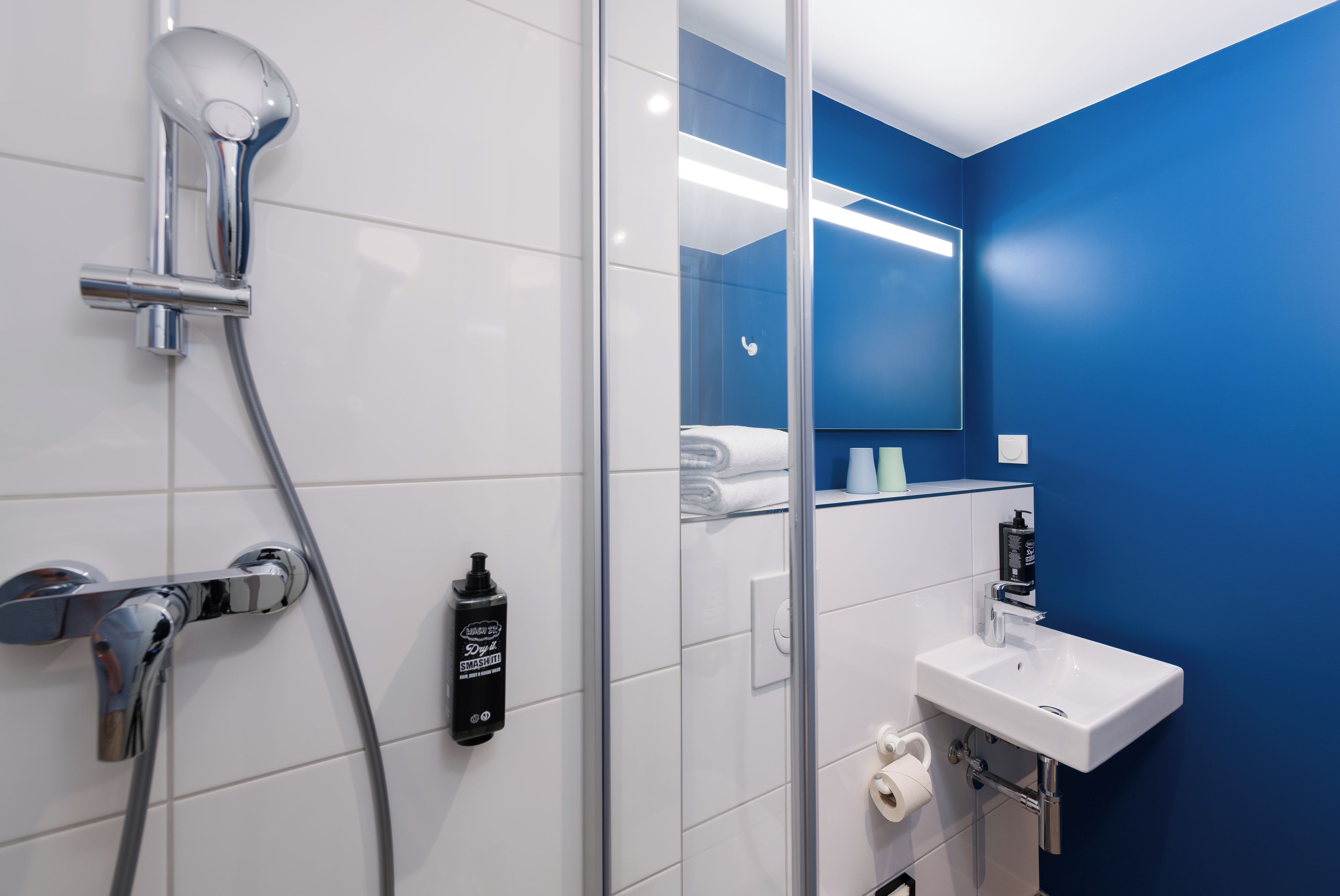 Un baño moderno con ducha, lavamanos y espejo.