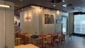 Un interior moderno con mesas y sillas, obras de arte en las paredes y vistas a través del ventanal.
