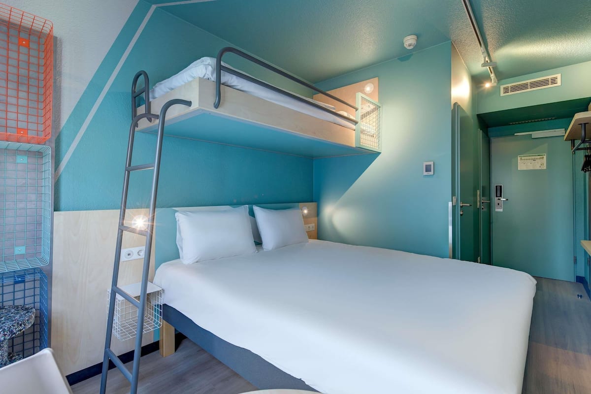 A bunk bed room with a ladder, a desk, and a door.