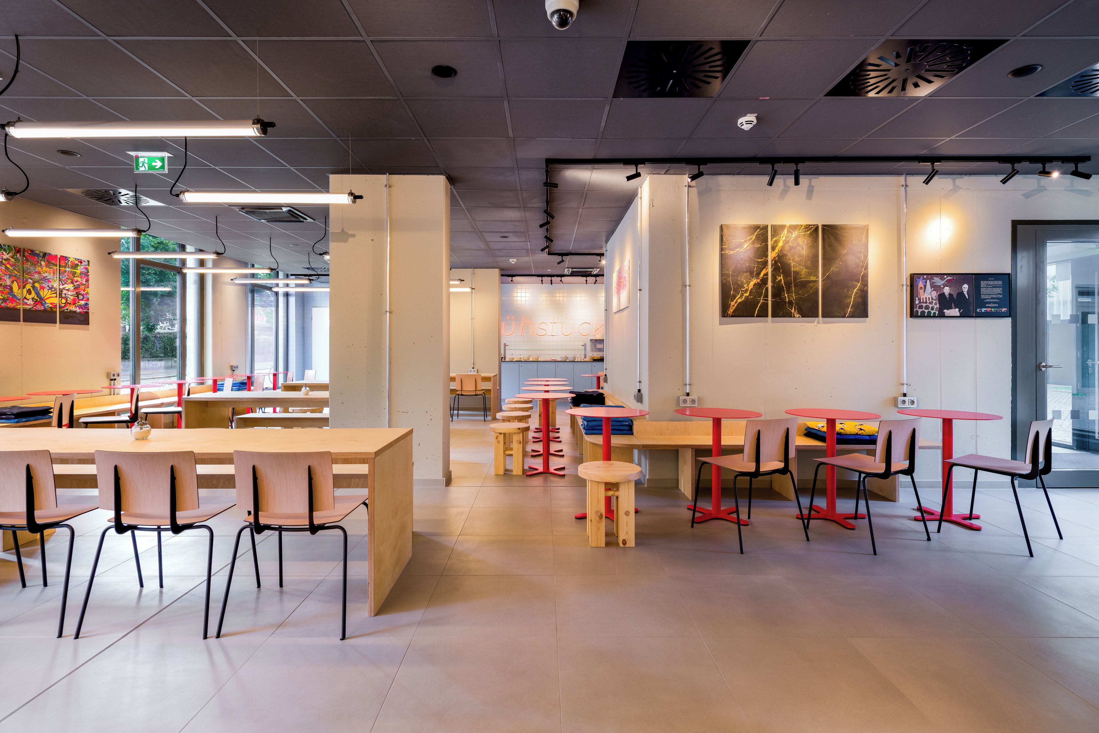 A modern interior with high ceilings, exposed ductwork, and a mix of seating arrangements including tables and chairs.