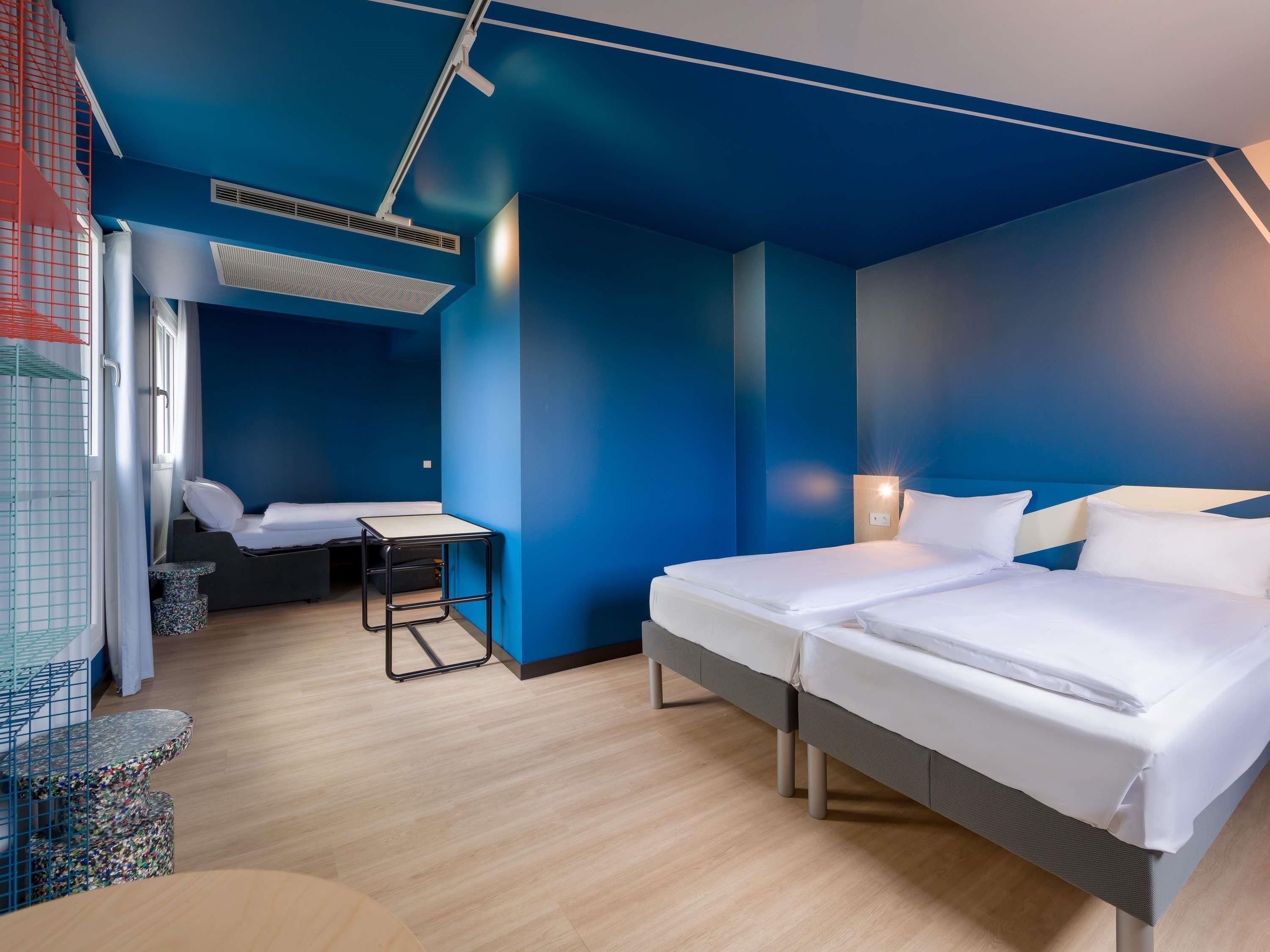 Ein Hotelzimmer mit zwei Betten, einem Schreibtisch und einem Stuhl.