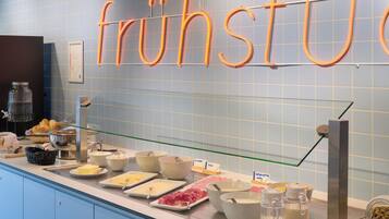 Een ontbijtbuffet met diverse gerechten en een bord waarop staat 'fruhstu'.