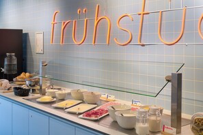 Un bufé de desayuno con diversas opciones de comida y un letrero que dice 'fruhstu'.