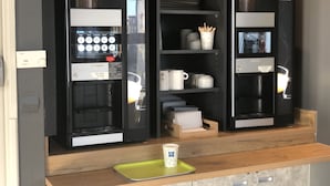 A coffee machine with a digital interface and a cup of coffee on a tray. - ibis budget Paris Porte de Montreuil (Montreuil)