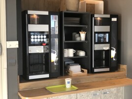 Una cafetera con pantalla digital y una taza de café sobre una bandeja.