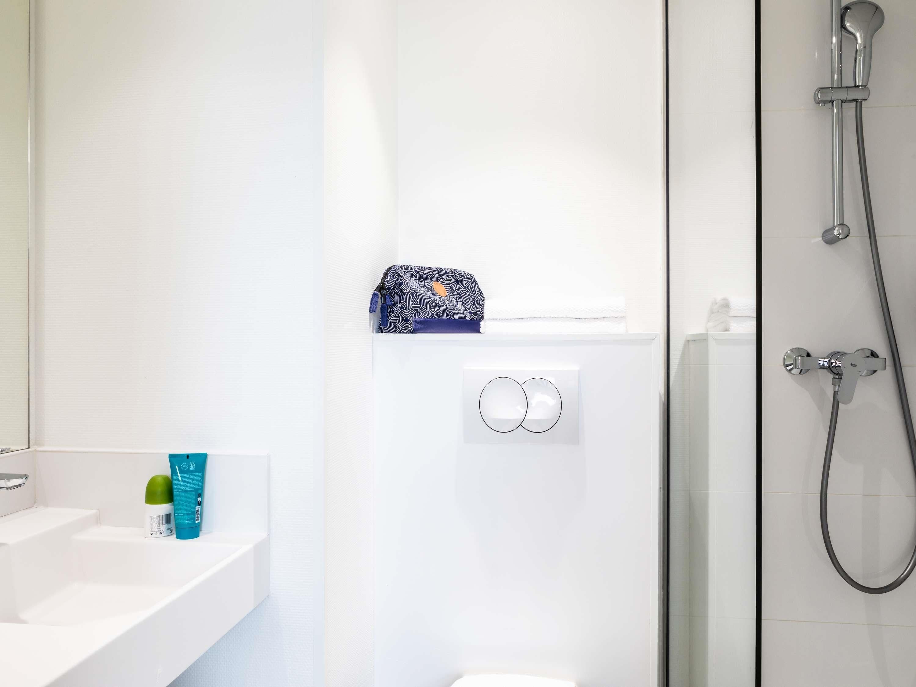 A bathroom with a white sink, a glass shower enclosure, and a towel rack.
