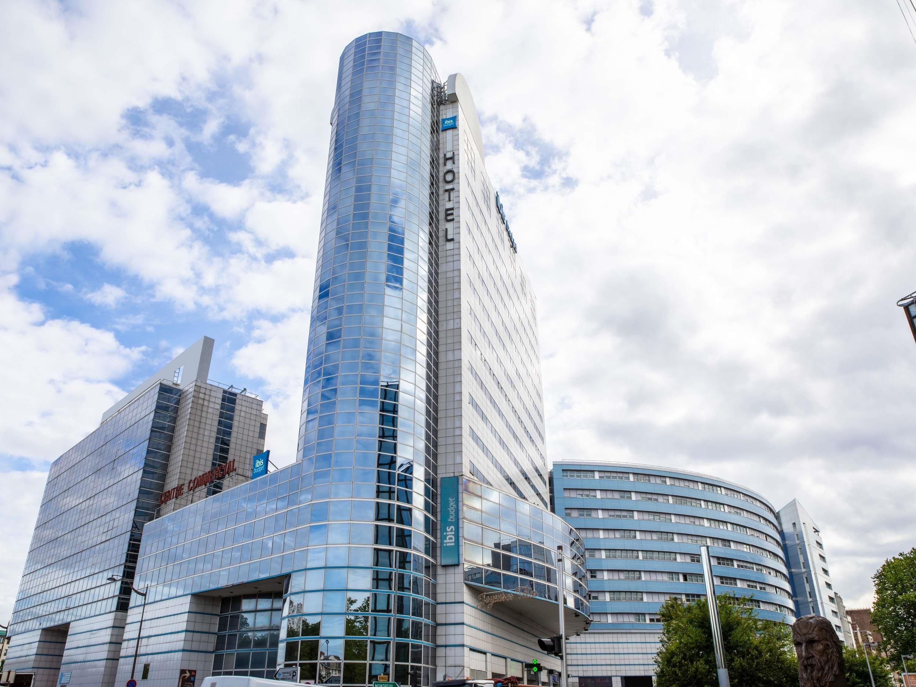 Een modern hotel met een gebogen glazen gevel, een opvallend 'HOTEL' bord en een 'CATHOLIC COMMISSION' bord op een nabijgelegen gebouw.