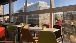 A modern dining area with large windows, colorful chairs, and tables. - ibis budget Paris Porte de Montreuil (Montreuil)