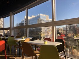 Un comedor moderno con ventanas amplias, sillas coloridas y mesas.