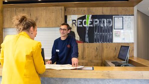 A reception desk with a wooden counter, a computer, and a map. - ibis budget Paris Porte de Montreuil (Montreuil)