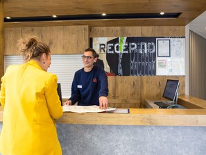 A reception desk with a wooden counter, a computer, and a map. - ibis budget Paris Porte de Montreuil (Montreuil)