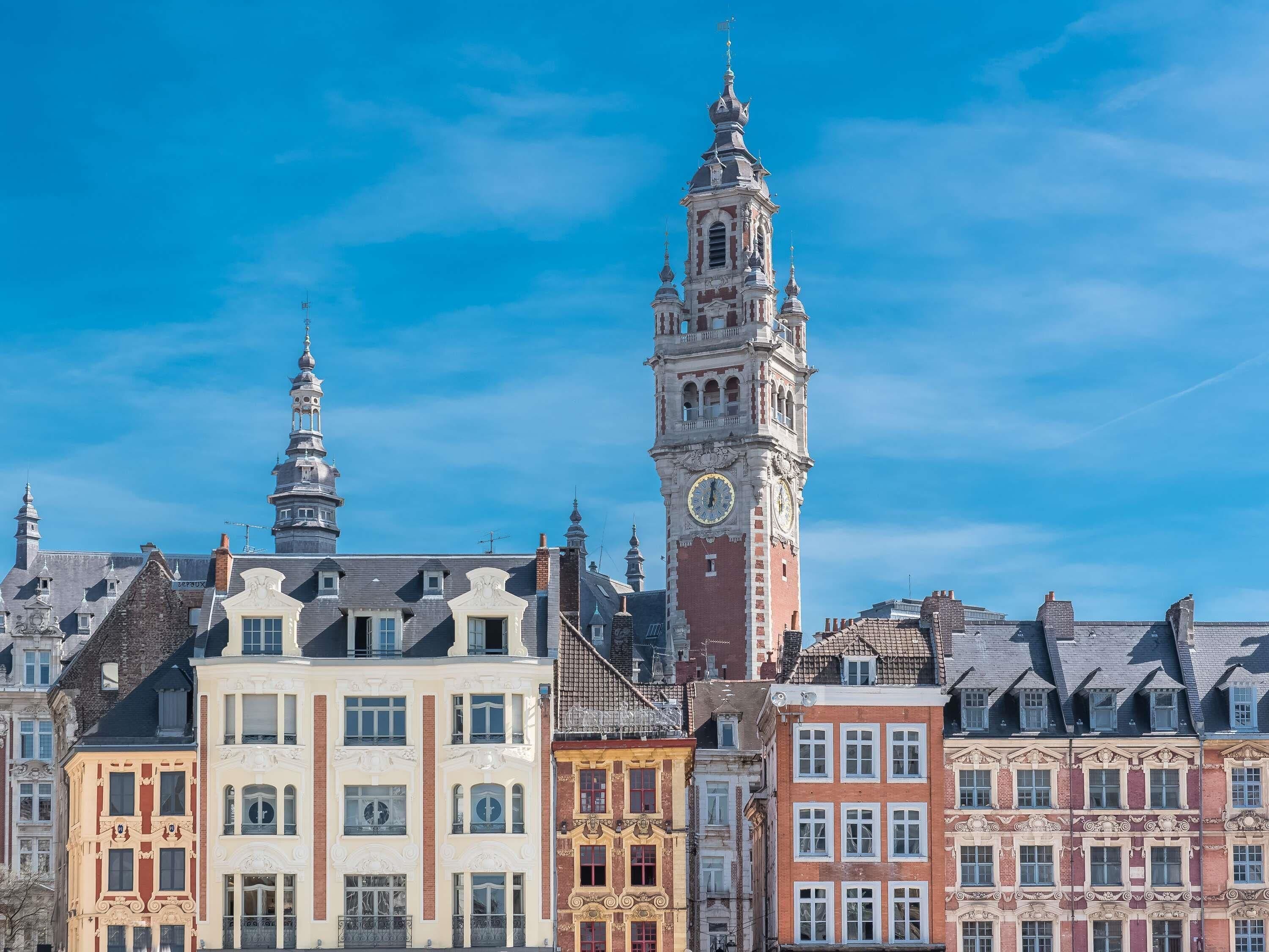 Una torre històrica amb un rellotge, envoltada d'arquitectura europea clàssica.