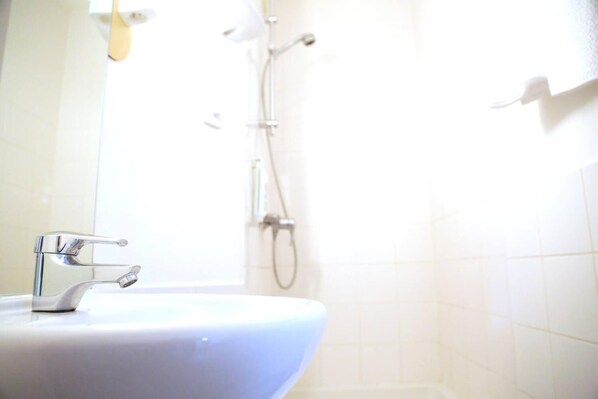 A bathroom with a white sink, a shower, and a toilet. - ibis budget Lille Villeneuve d'Ascq (Villeneuve-d'Ascq)