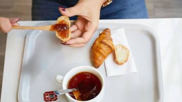 A tray with a croissant, a slice of bread with jam, and a cup of tea.