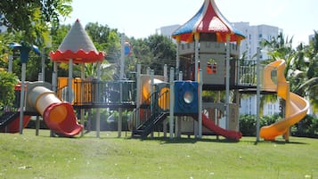 Explore the playground's climbing area, slides, and pavilion in a secure, grassy setting.