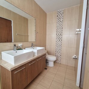 Un baño con dos lavamanos, un inodoro y un espejo.