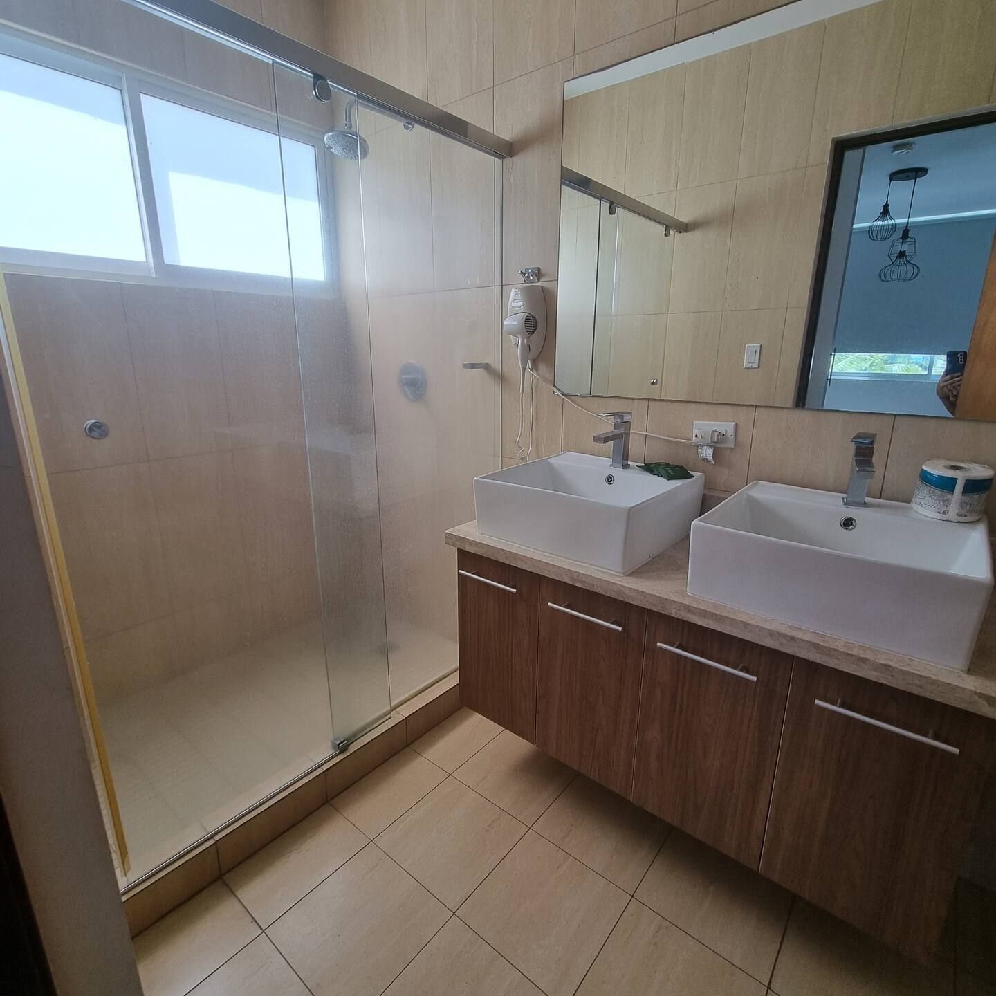 A modern bathroom with a glass-enclosed shower, two sinks, and a large mirror.