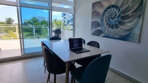 Un espacio de oficina moderno con un gran ventanal, una laptop sobre una mesa y una obra de arte en espiral en la pared.