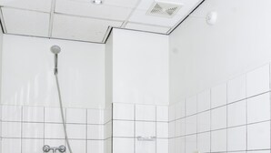 A bathroom with a shower, toilet, and checkered floor. - Boom Apartments (Paramaribo)
