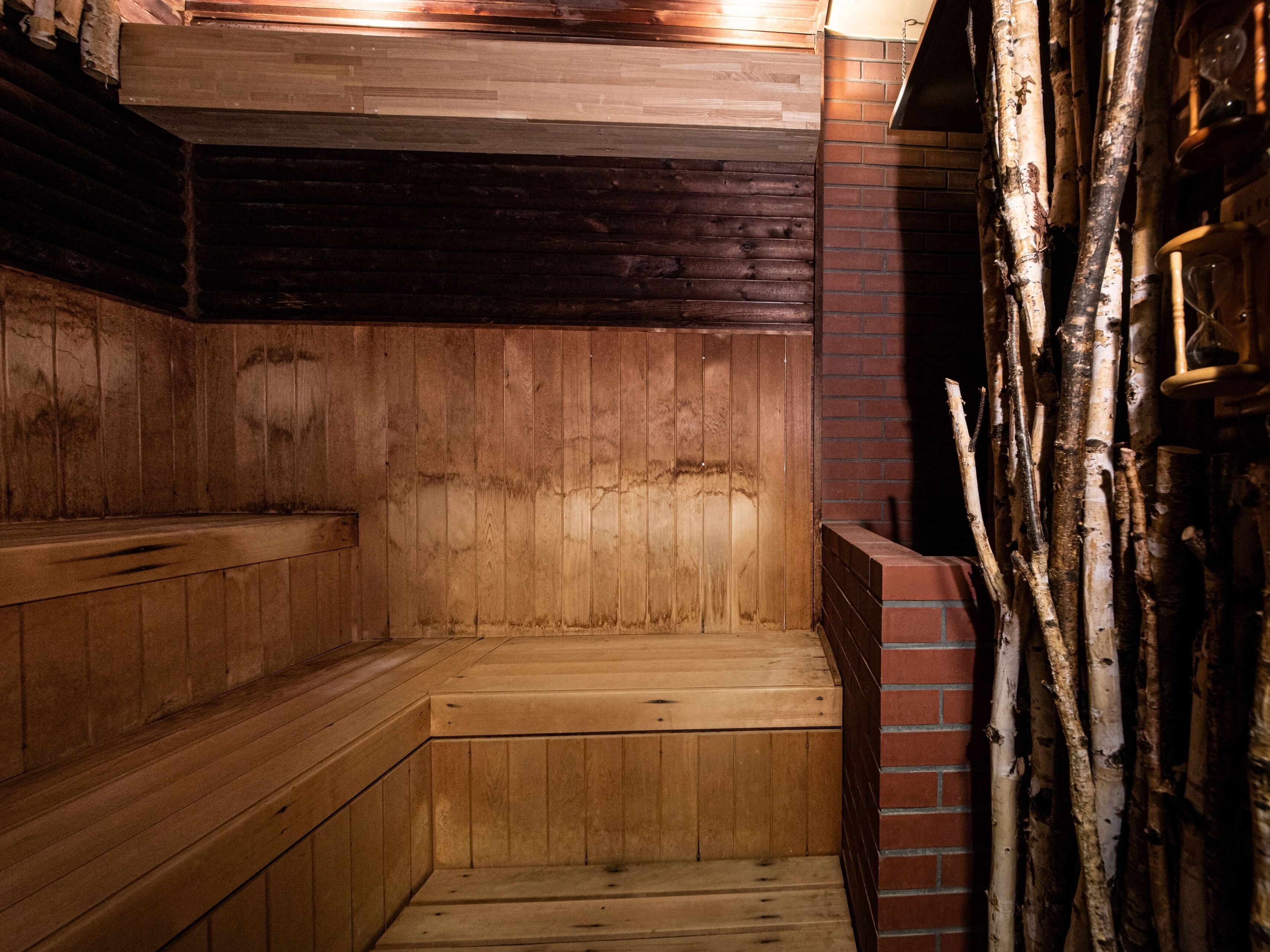 A sauna with wooden benches and a brick wall.