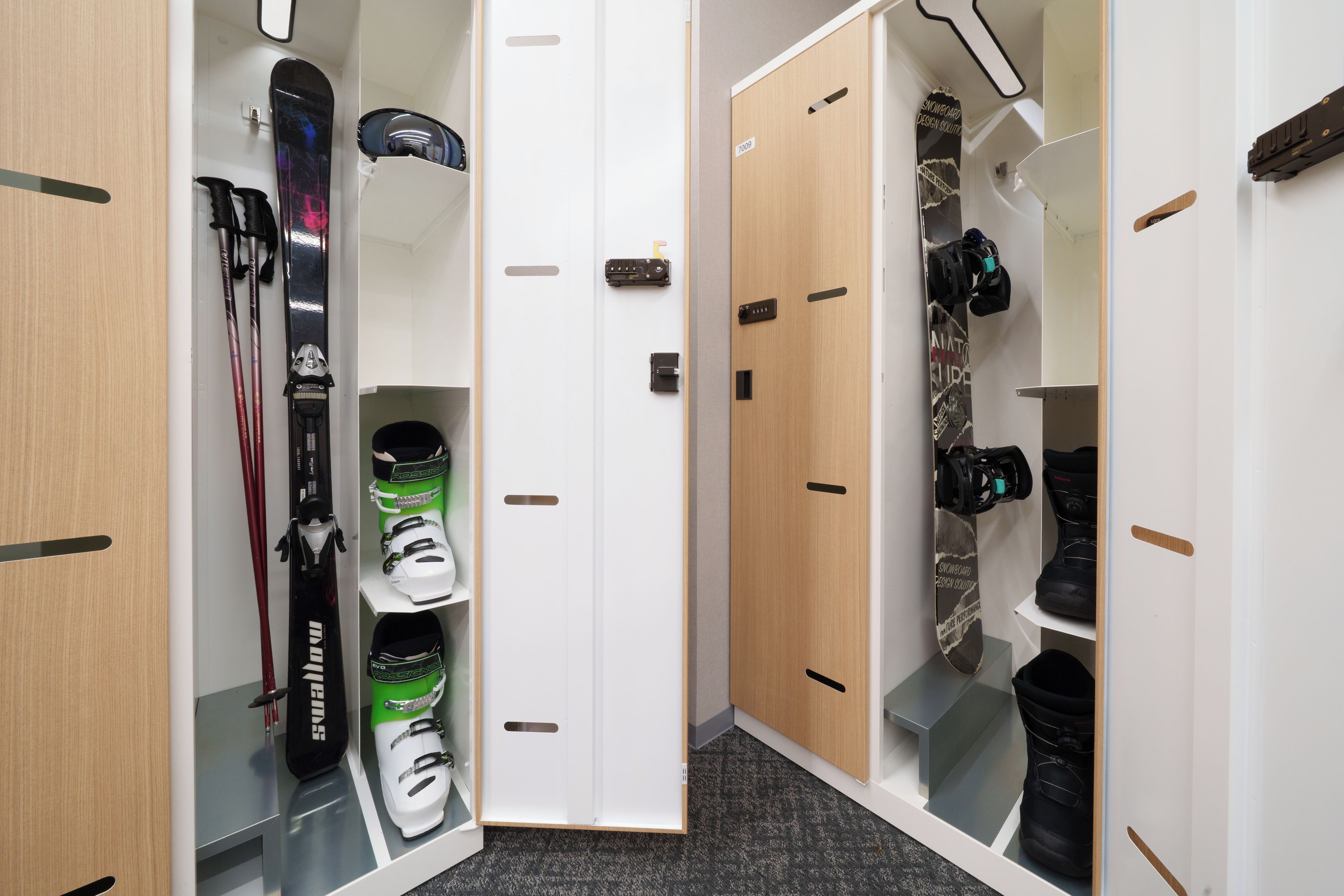 A storage closet with ski equipment, including skis, boots, and snowboards.