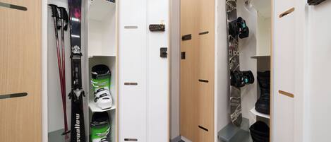 A storage closet with ski equipment, including skis, boots, and snowboards.