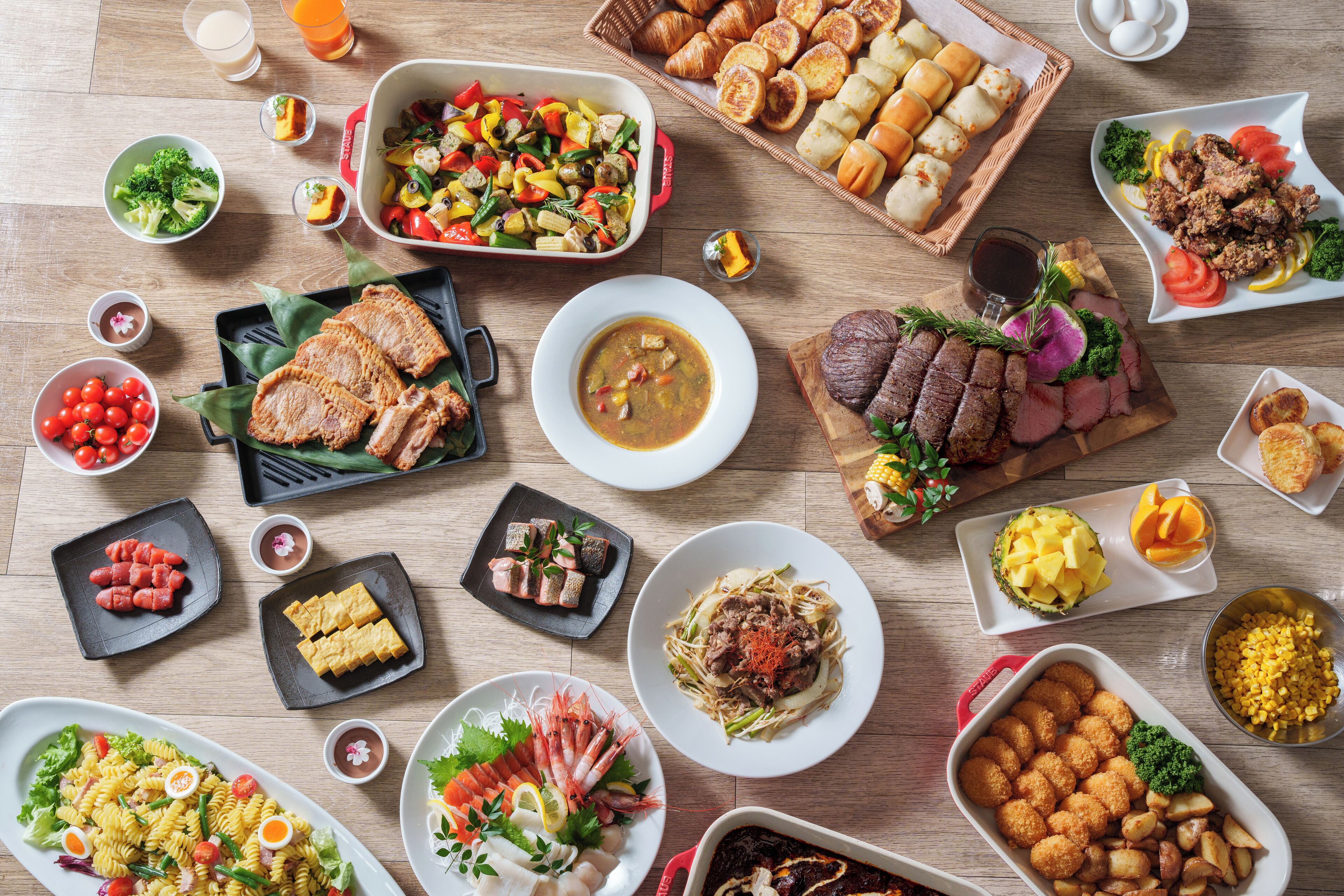 Diverse gerechten, waaronder pasta, vis en brood, gepresenteerd op een houten tafel.