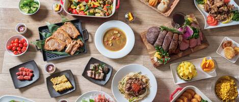 Diverse gerechten, waaronder pasta, vis en brood, gepresenteerd op een houten tafel.