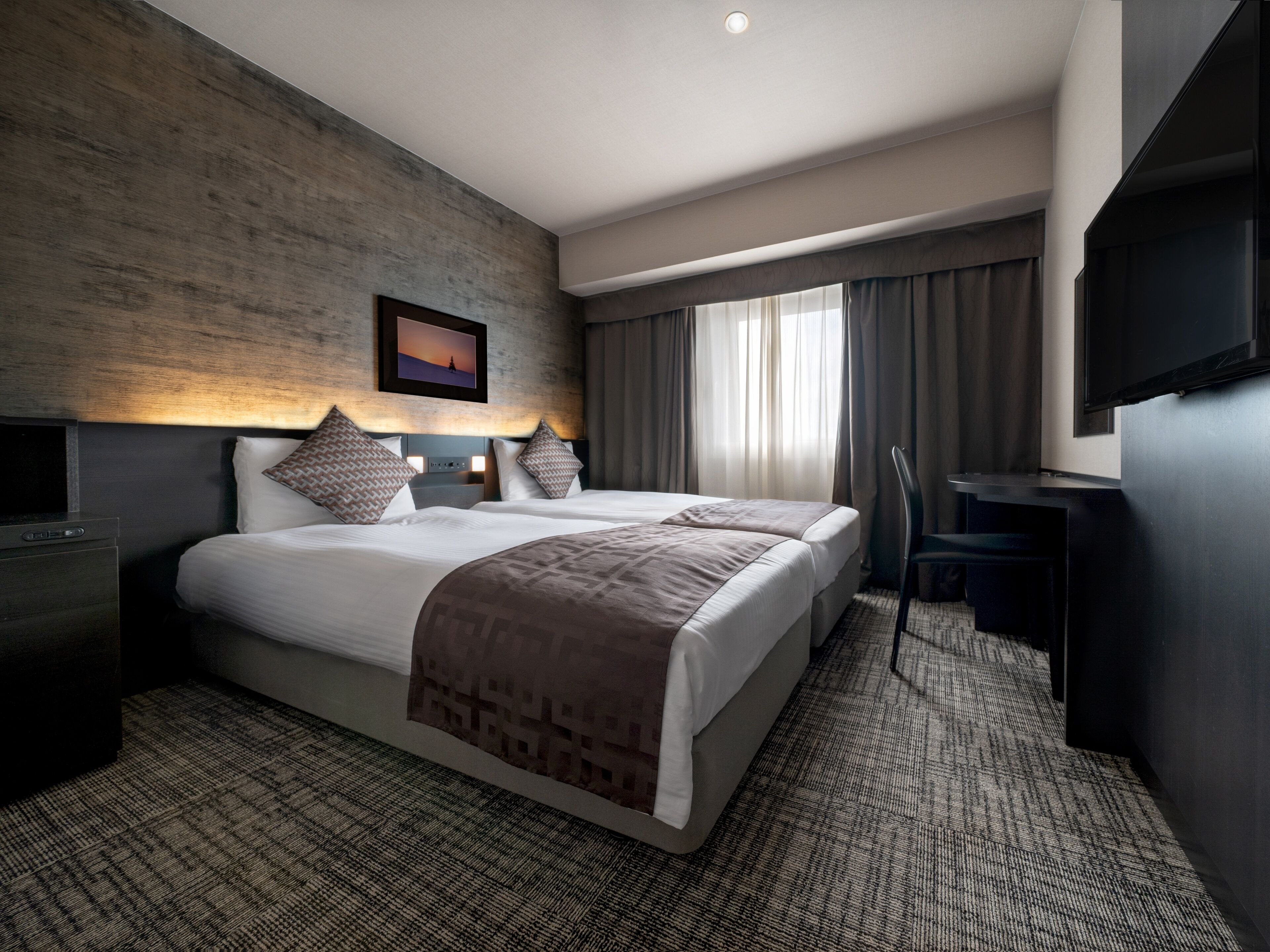 A modern hotel room with a large bed, a desk, and a flat-screen TV.